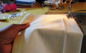 The left hand gently moves the fabric forward as it is fed through the machine.